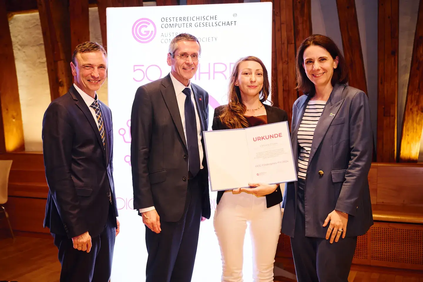 Ronald Bieber, Wilfried Seyruck und Sylvia Geyer übergeben den OCG Förderpreis-FH2024 an Viktoria Frank.