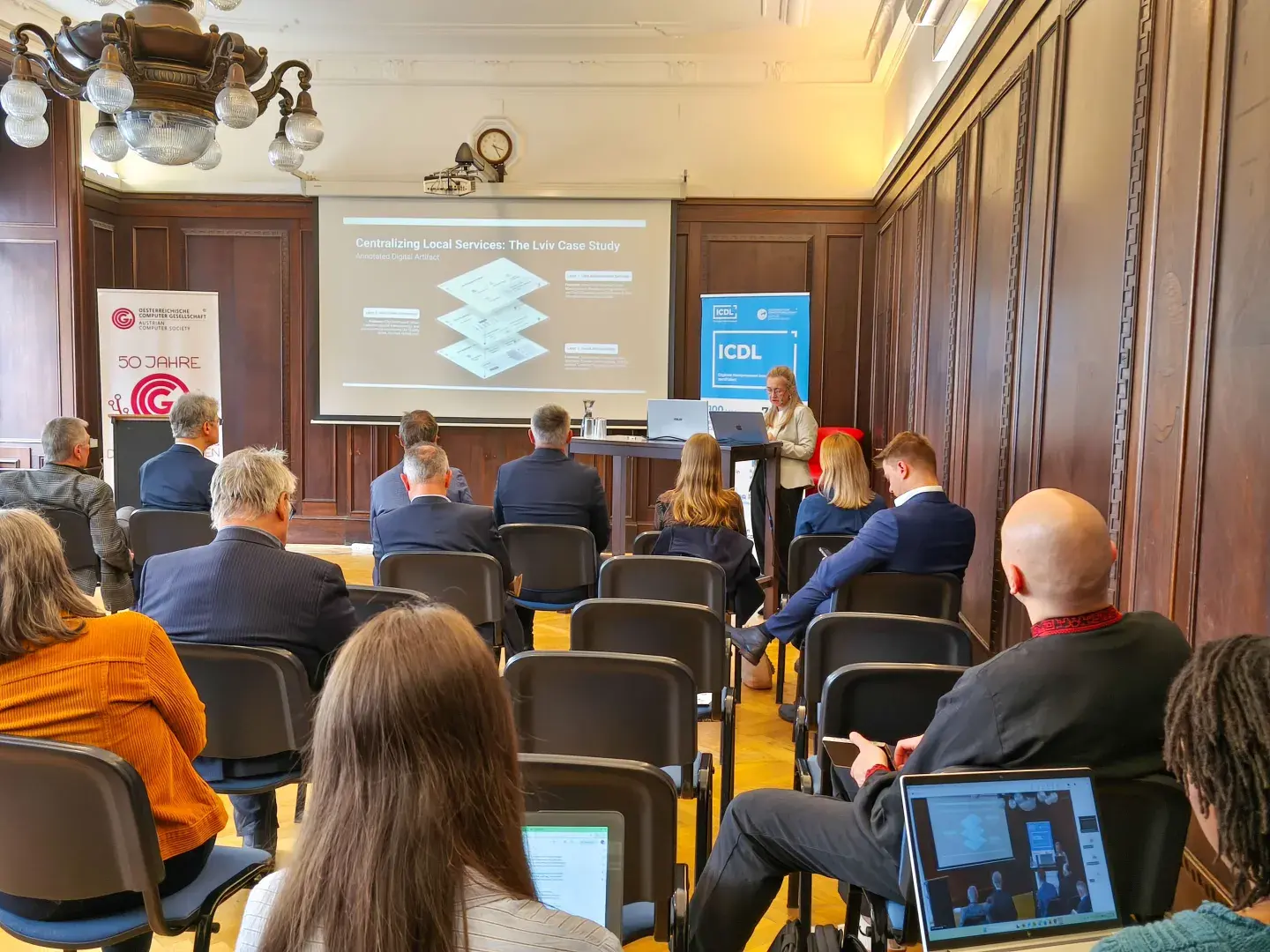 Lidiya Lisovska hält einen Vortrag im Heinz Zemanek Saal der OCG, Hinterköpfe des Publikums, Präsentation auf Beamer