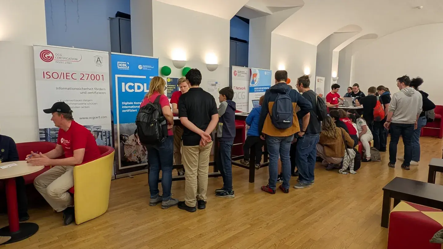 Besucher*innen bei der LNF26 in der OCG stehen vor den Stationen