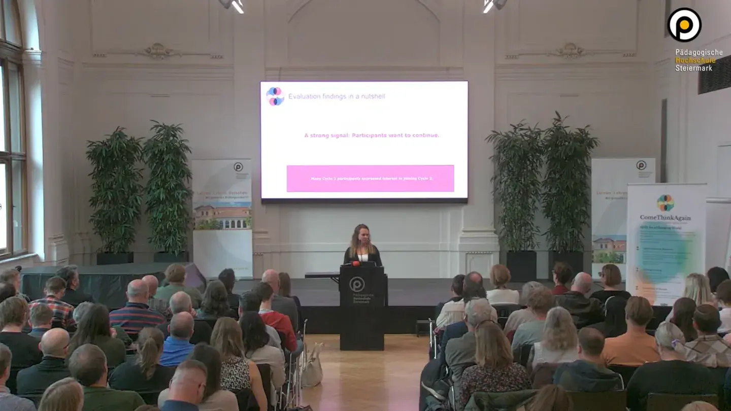 Foto zeigt voll besetzten Saal, Publikum von hinten, Speaker auf der Bühne: Sandra Tomeschek (OCG) stellt am Tag der digitalen Bildung die ersten Ergebnisse des ComeThinkAgain Projekts vor (c) PH Steiermark