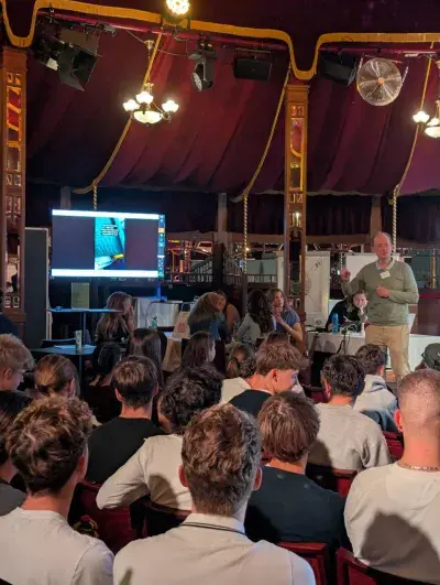 Gruppe von Schüler*innen mit Wilfried Baumann beim KI Workshop im MIRAGE Zirkuszelt
