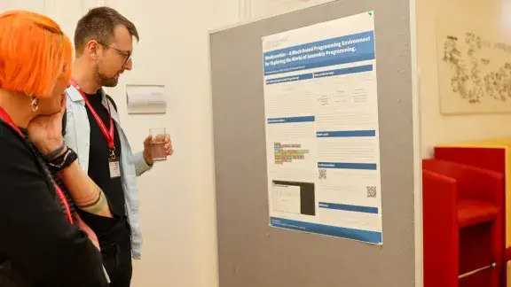 Zwei Personen lesen aufmerksam ein Poster aus der Poster Session