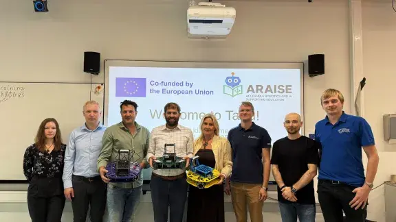 Kick-off ARAISE Projekt: Gruppenfoto mit 8 Personen, darunter Martin Kandlhofer, drei Personen halten Roboter in der Hand, im Hintergrund zeigt Leinwand das ARAISE Logo sowie die Info, dass es ein Erasmus+ Projekt ist