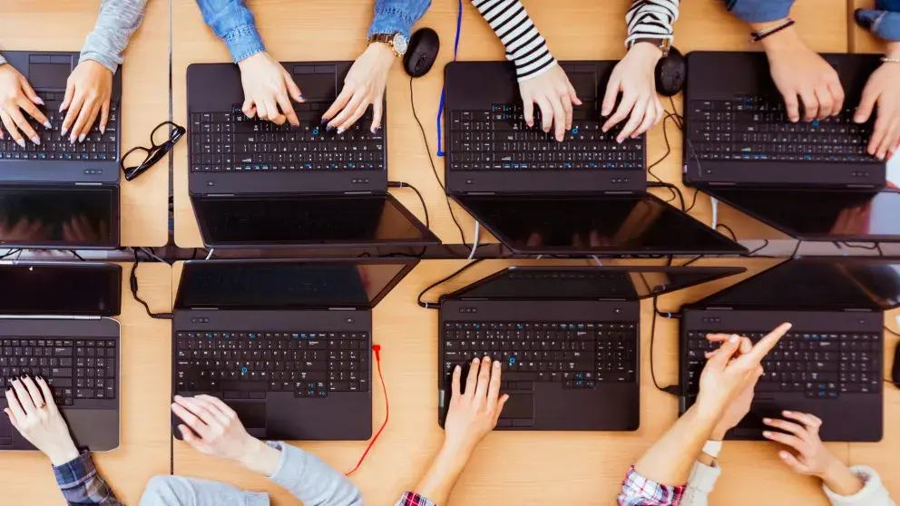 vier aufgeklappte Laptops jugendliche Hände tippen stock photo